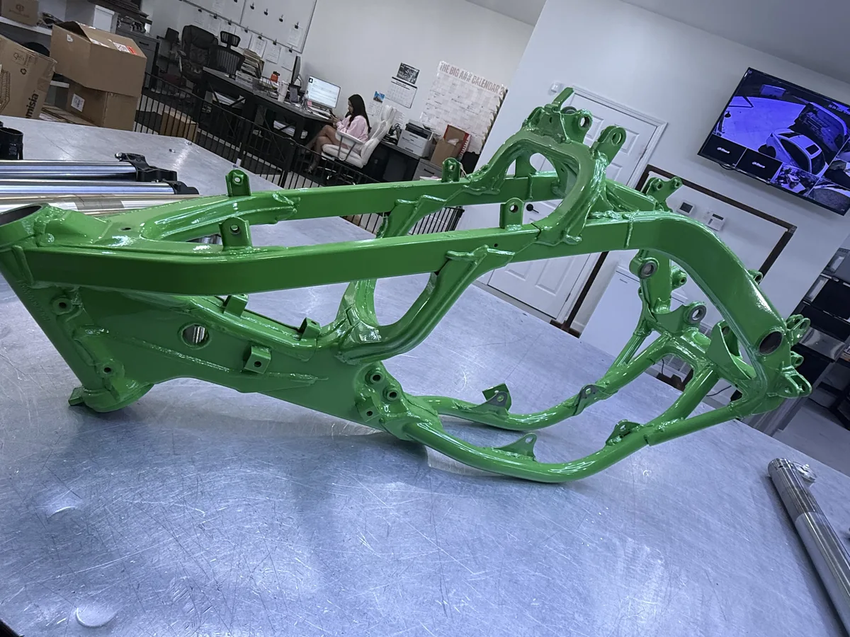 Green coated motorcycle frame on a shop table